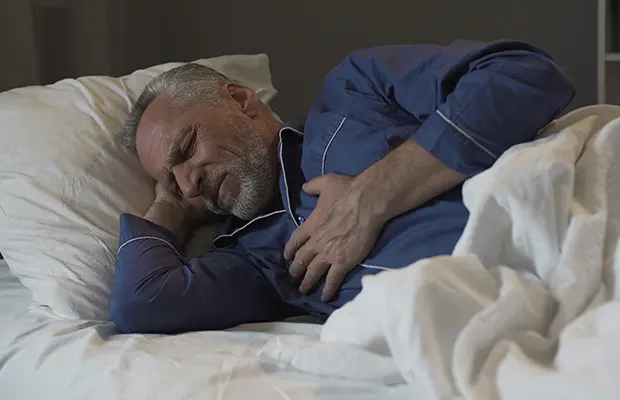 "صورة توضح رجل يمسك صدره مع ظهور علامات ألم الصدر، لتوضيح متى يكون السبب مشاكل القلب وأهمية التدخل الطبي السريع."